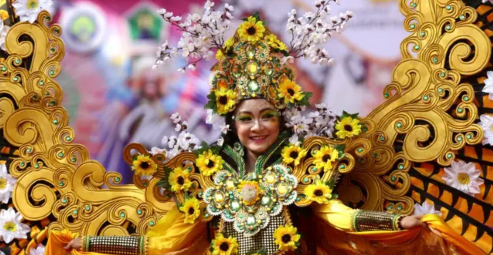 Festival budaya lokal dengan pertunjukan seni tradisional dan masyarakat mengenakan pakaian adat Indonesia